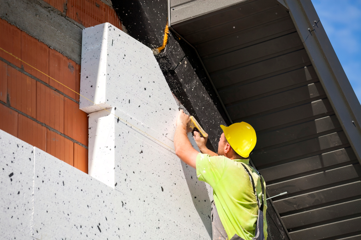 Ein Bauarbeiter bringt eine Fassadendämmung an