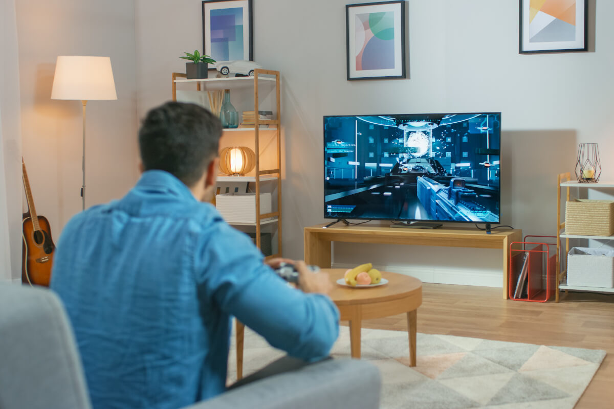 Im Wohnzimmer Mann sitzt auf einer Couch hält Controller spielen in einer Konsole Videospiel
