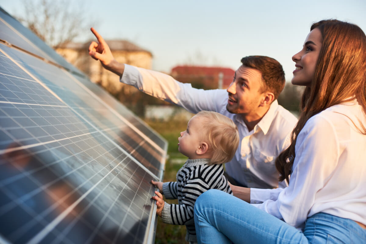 Ein Mann zeigt seiner Familie die Sonnenkollektoren auf dem Grundstück neben dem Haus